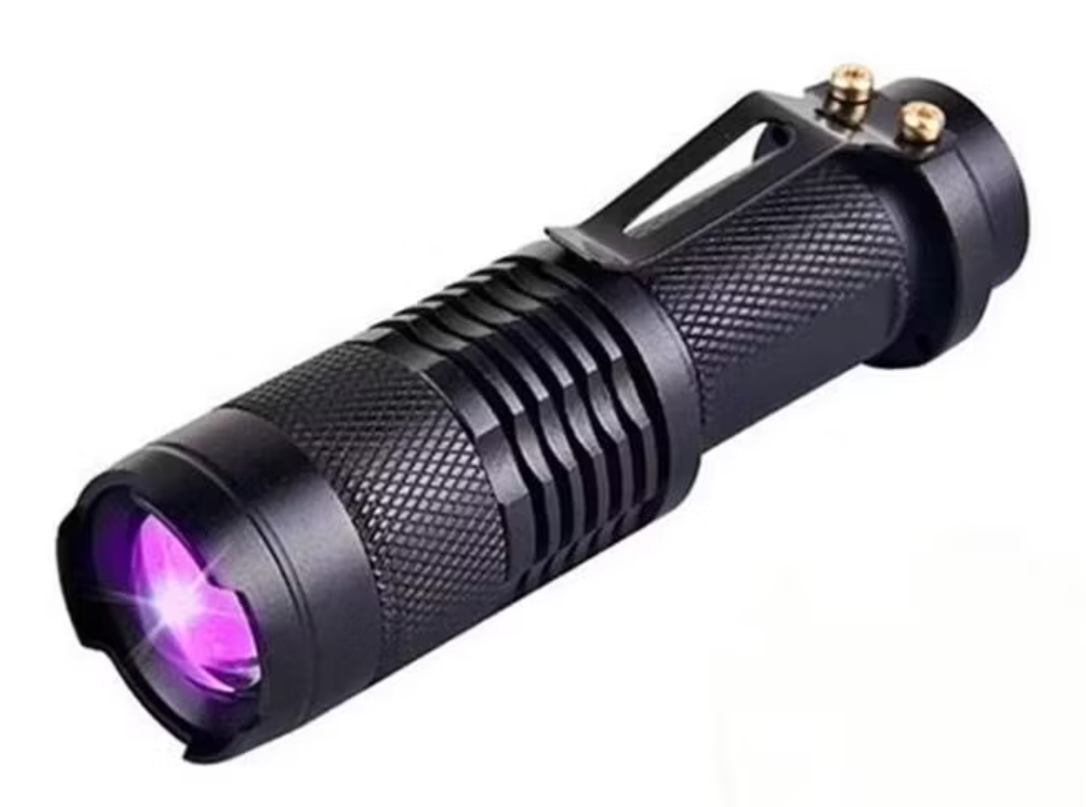 Black flashlight with purple light on a white background