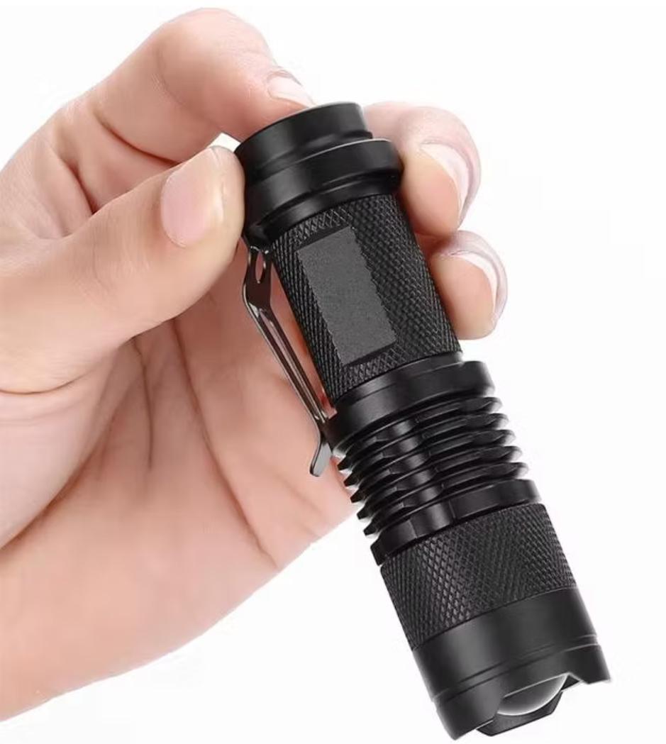 Black flashlight held in a hand against a white background