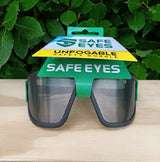 Safe Eyes safety goggles with packaging on a wooden surface and green leafy background